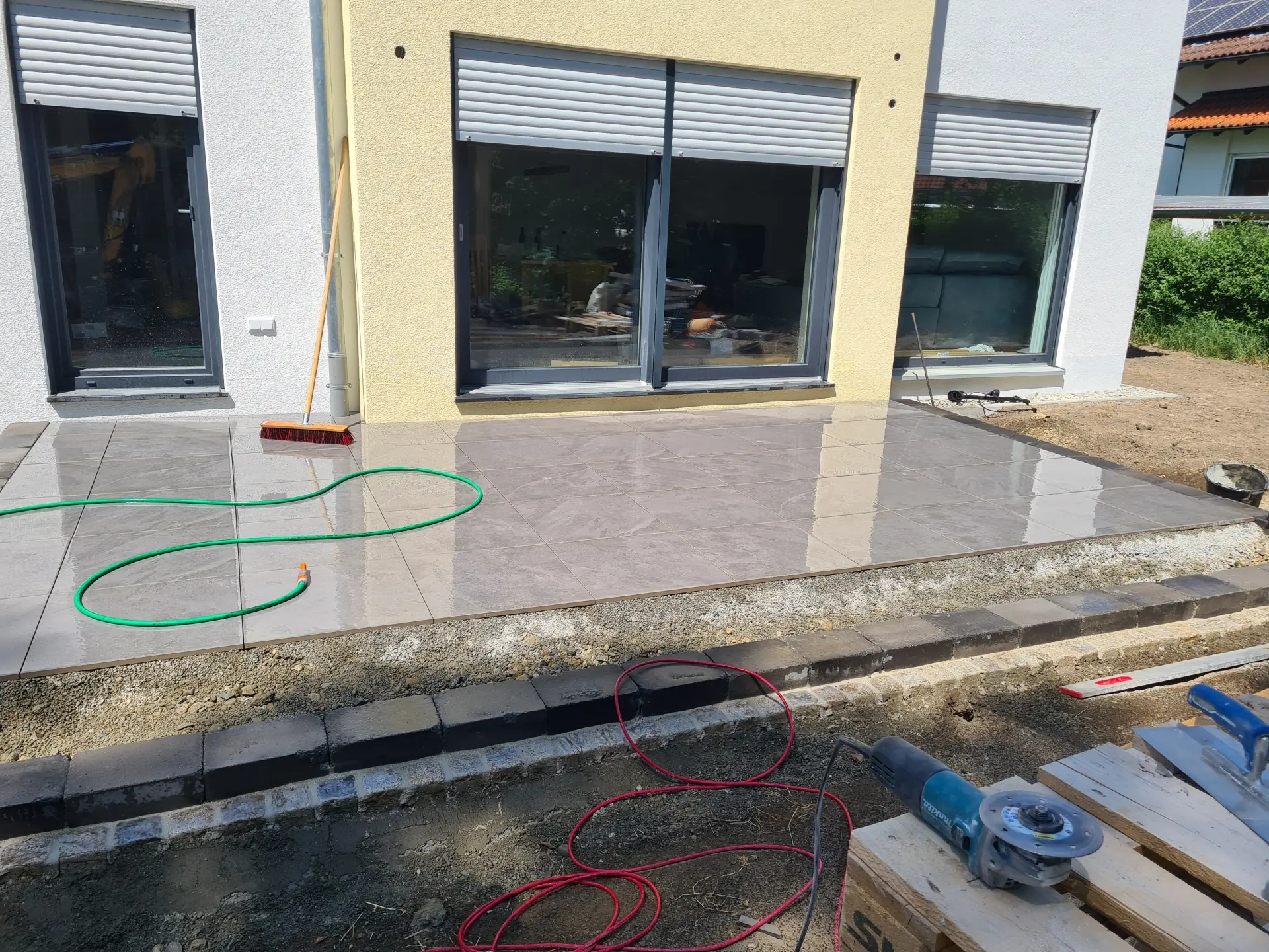 Terrasse mit grauem Plattenbelag als Teil einer neu gestalteten Außenanlage