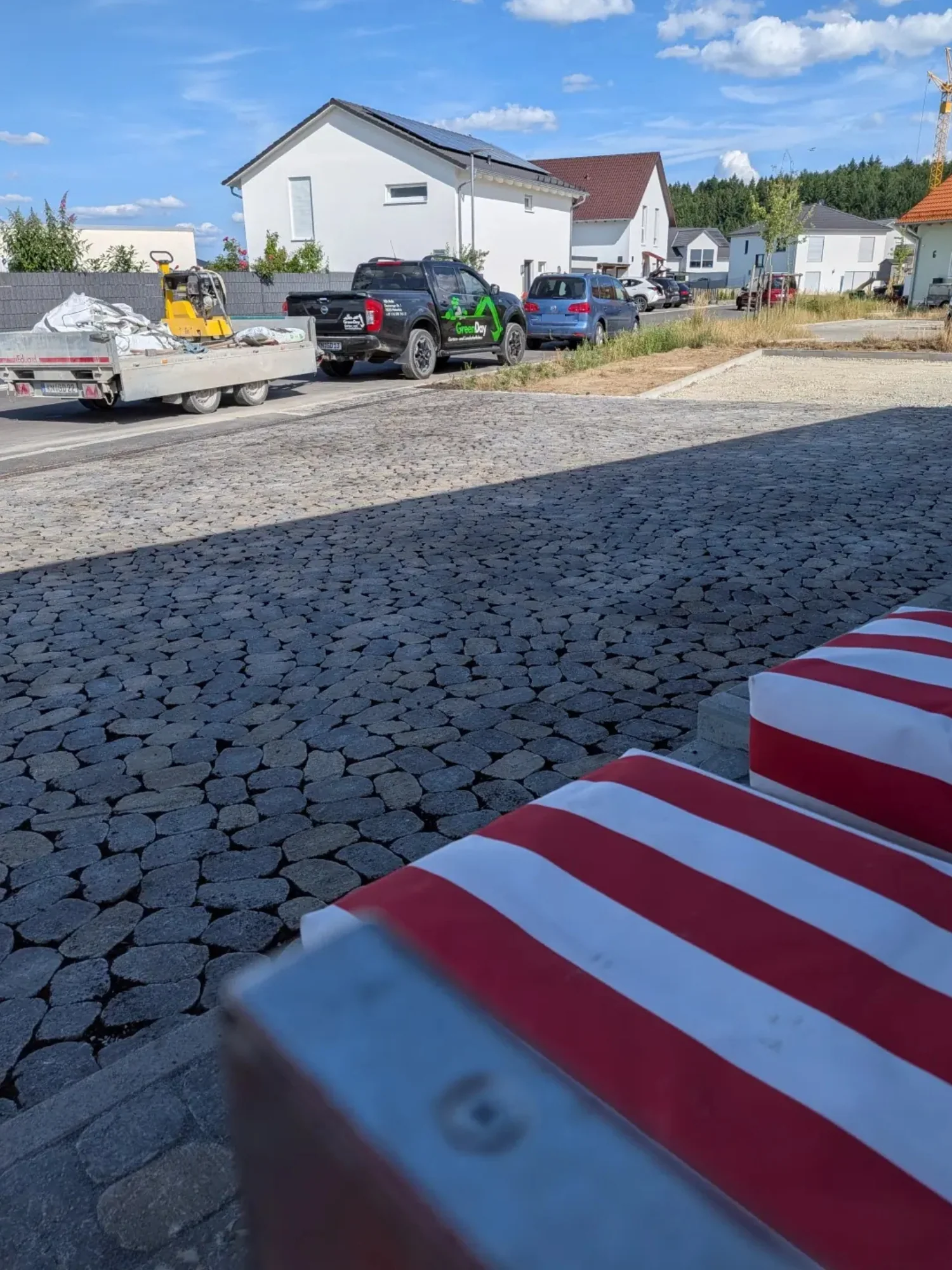 Neu gestalteter Eingangsbereich mit gepflasterter Einfahrt und Sitzgelegenheiten vor dem Haus